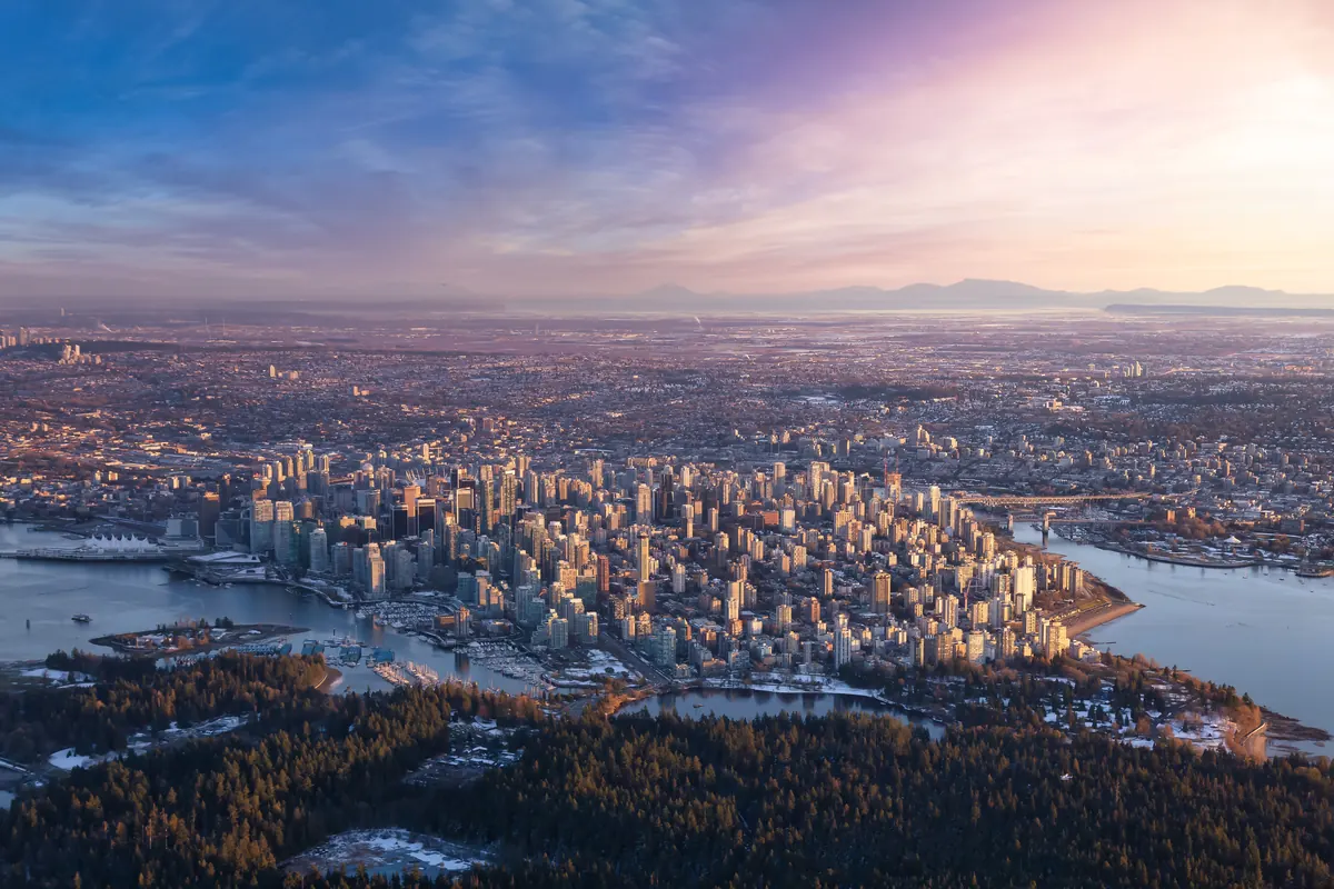 Aerial view of downtown Vancouver and the West End at dusk, with the North Shore mountains behind