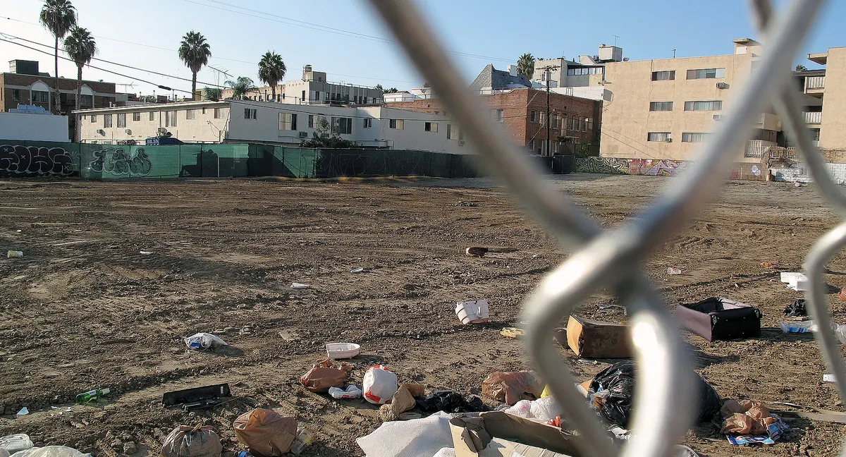 An empty city lot behind a chain-link fence