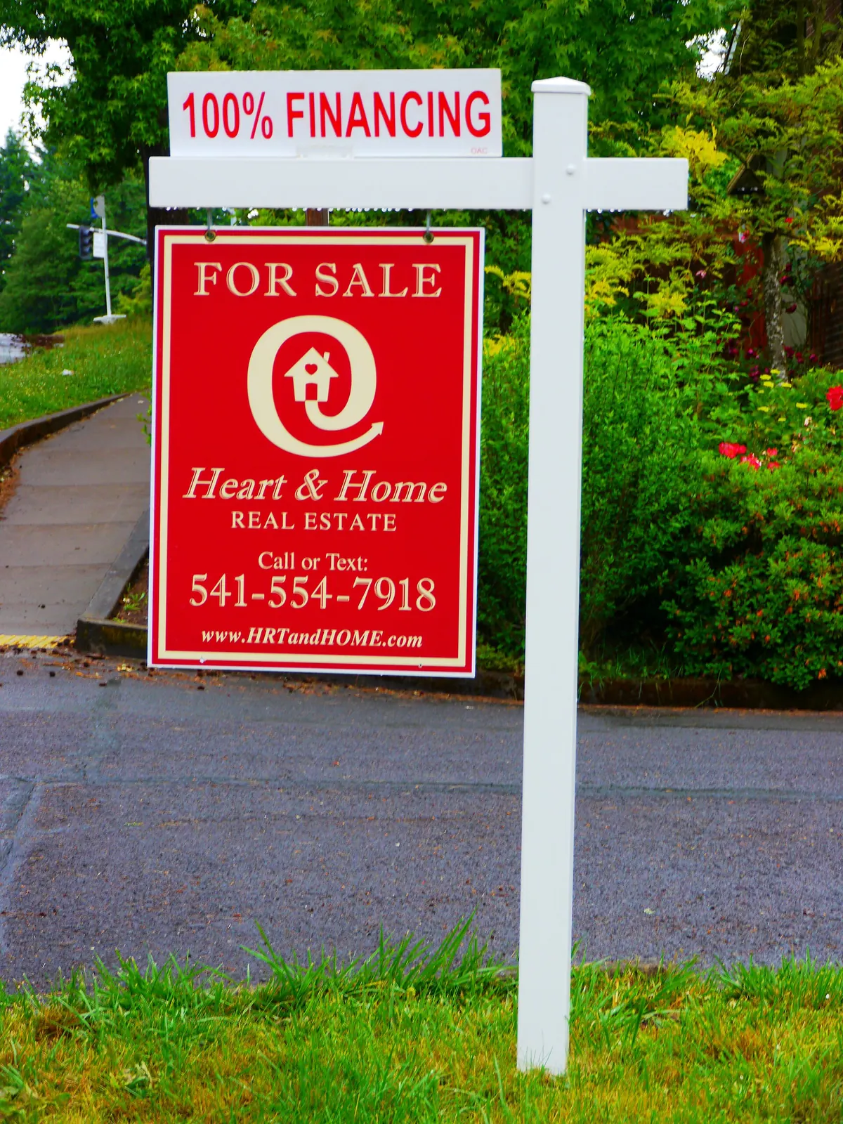 A For Sale sign on the lawn in front of a house
